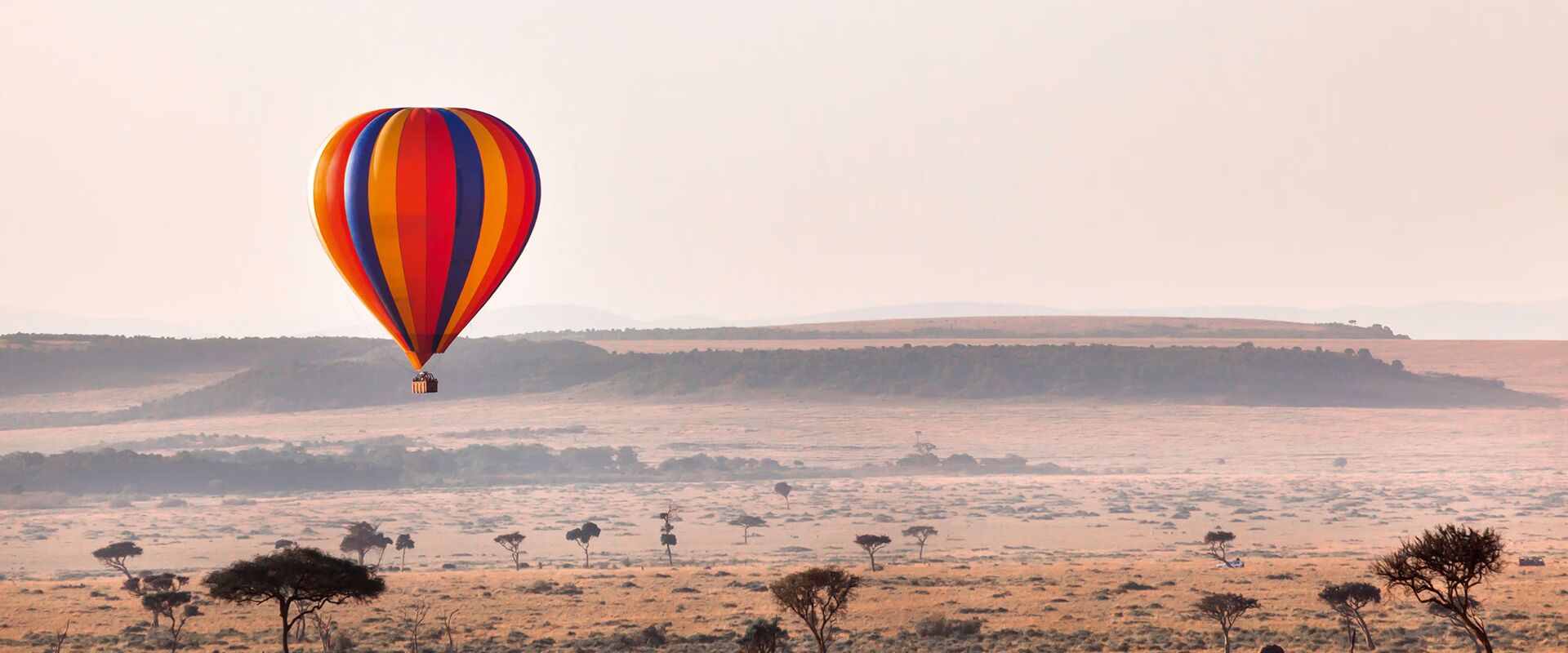 Above the Mara, Kenya — a hot-air balloon at sunrise, then breakfast in the bush